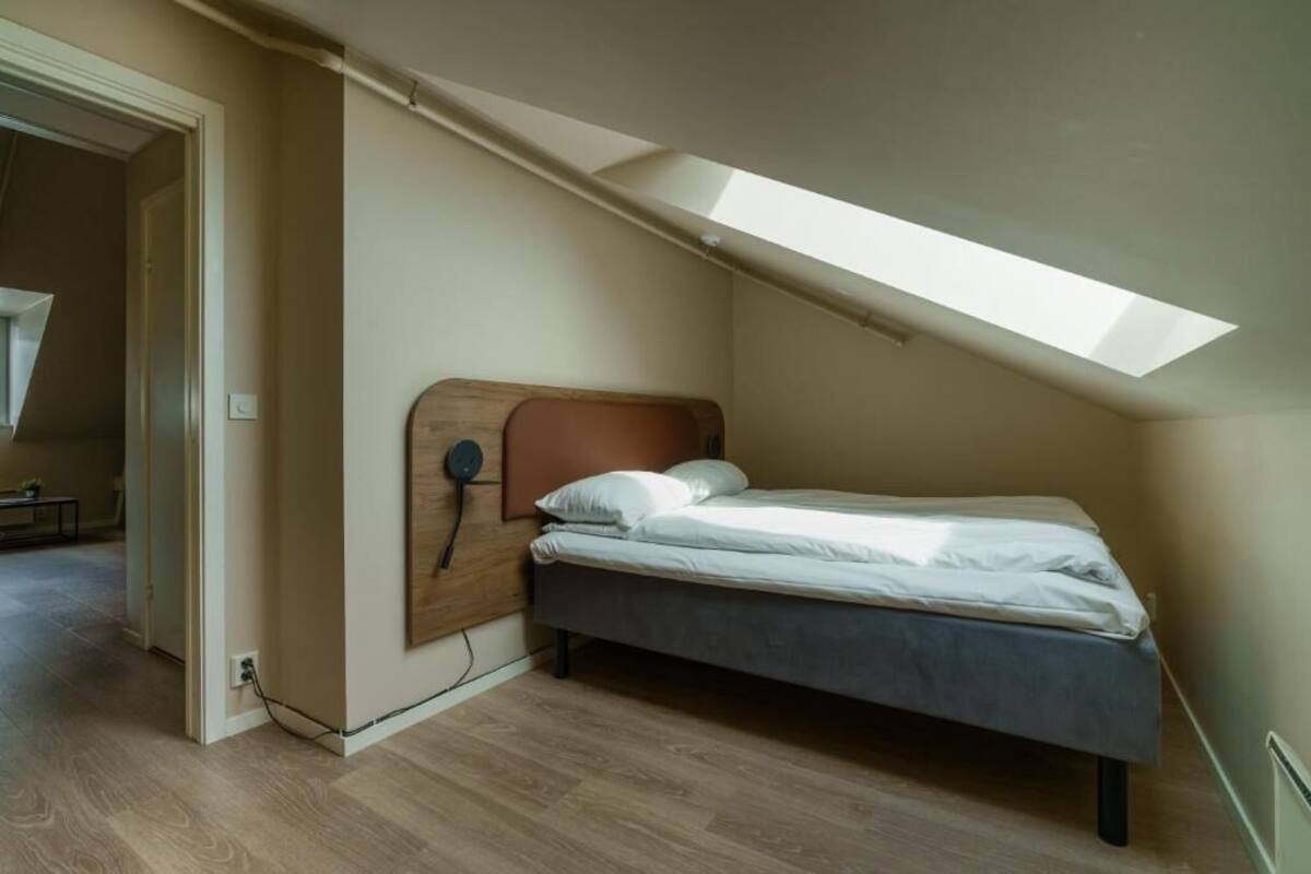 Ein Schlafzimmer mit schrägem Dach, einem Bett und einem Oberlicht.
