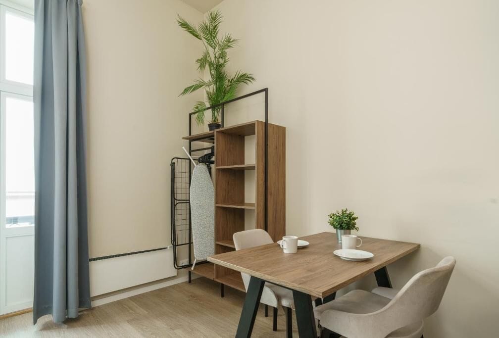 Een eethoek met een houten tafel, stoelen, een potplant en een wandplank.