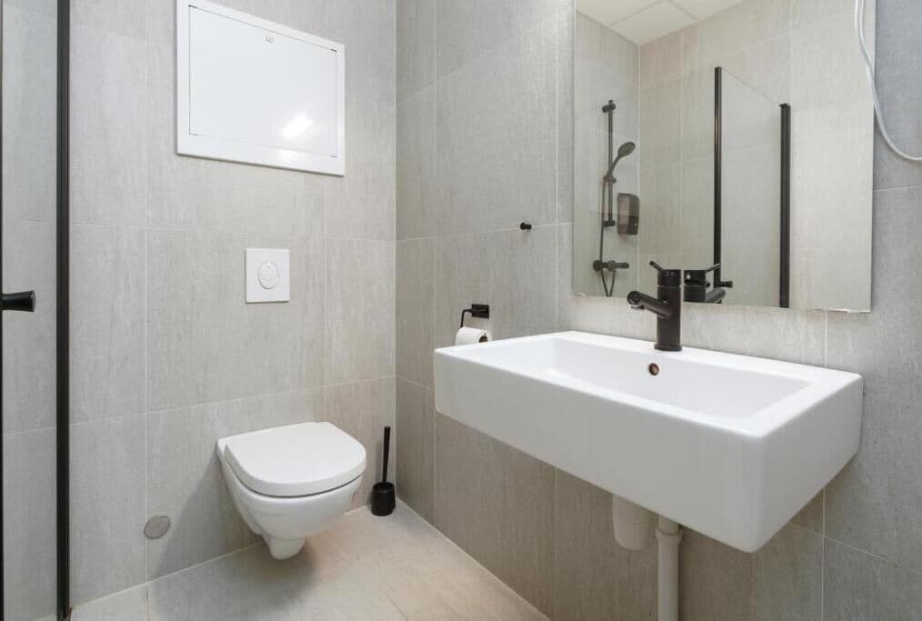 Un baño con inodoro, lavamanos y espejo.