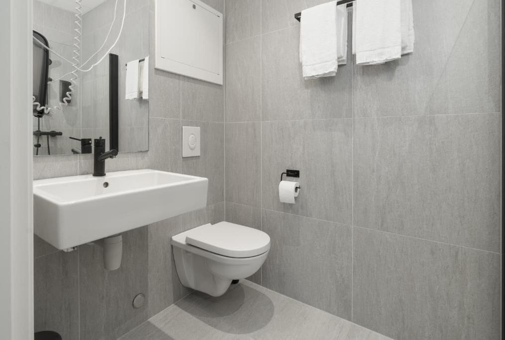 A modern bathroom with a white sink, toilet, and towel rack.