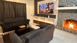 A modern living room with a fireplace, a flat-screen TV mounted on the wall, a sofa, and a coffee table. - Balay Tori & Gil (Baguio)