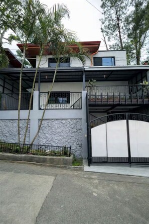 A two-story house with a stone facade, a gated entrance, and a balcony.