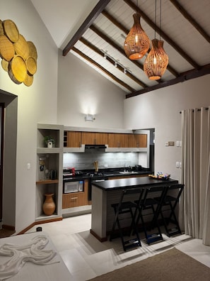 Une cuisine moderne dotée d’un îlot central, de meubles en bois et de luminaires suspendus.