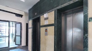 An interior hallway with two elevators, a door, and a sign on the wall. - Metro axis residency (Kathmandu)