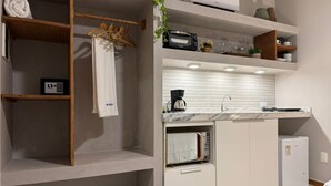 Een moderne keuken met een inbouwoven, een koffiezetapparaat en een kleine koelkast.