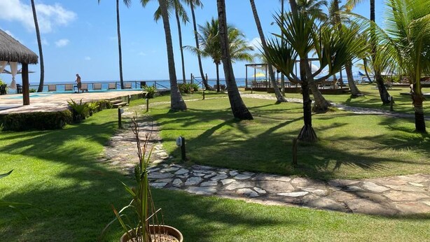 Un complexe hôtelier tropical doté de palmiers, d’un sentier en pierre et d’un espace piscine.