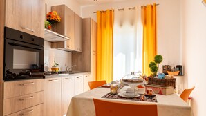 A modern kitchen with wooden cabinets, a built-in oven, and a dining area with a table set for two.
