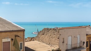 A coastal building with a tiled roof, a balcony, and a view of the sea.