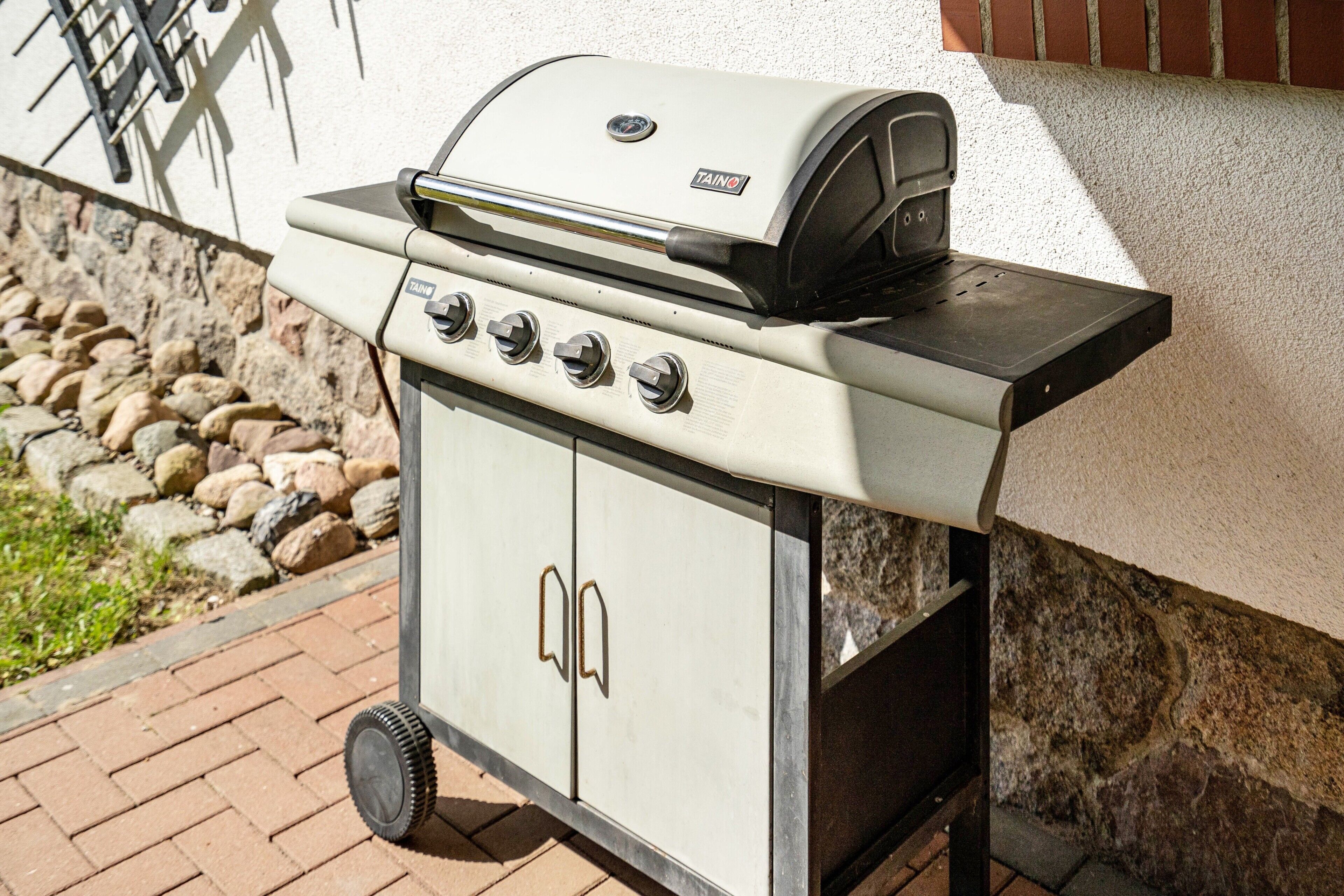 A portable gas grill with four burners and a digital display, mounted on a wheeled cart.