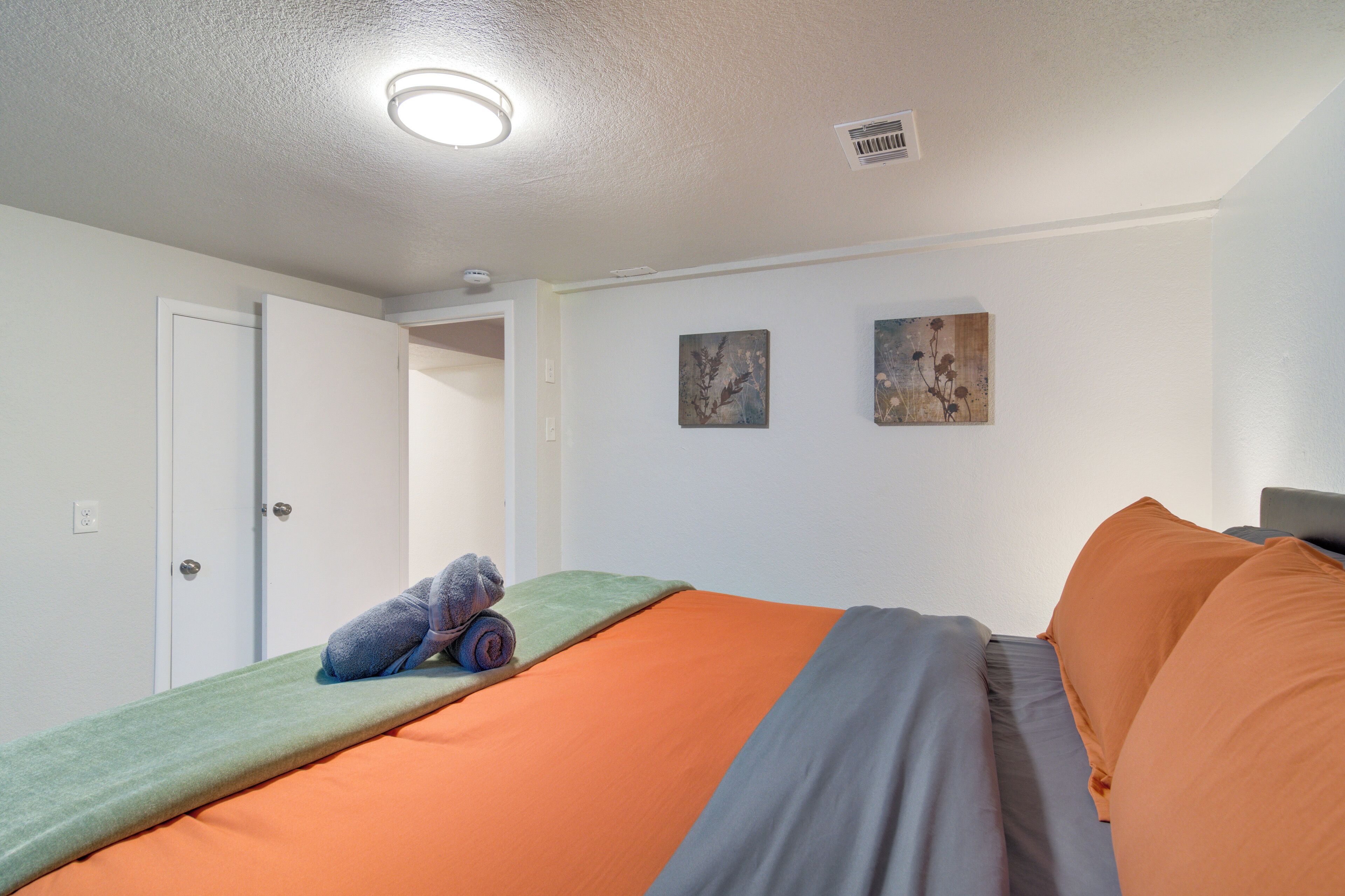 Een slaapkamer met een bed, een deur en twee kunstwerken aan de muur.