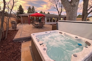 A hot tub in a backyard with a patio table and chairs, surrounded by trees and a house. - Hot Tub, Pool Table, BBQ Patio, Yard Games (Arvada)