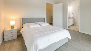 Un dormitorio con cama, mesita de noche y una puerta que da a otra habitación.