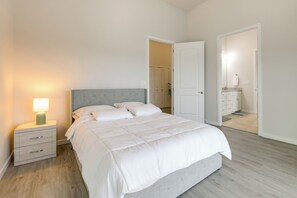 A bedroom with a bed, bedside table, and a door leading to another room. - Beautiful Lake Travis & Hill Country Views Home! (Leander)