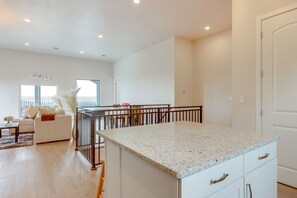 A spacious living room with a white sofa, a coffee table, and a dining area with a table and chairs. - Beautiful Lake Travis & Hill Country Views Home! (Leander)