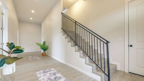 Una escalera con barandal negro, piso de madera y una puerta blanca.