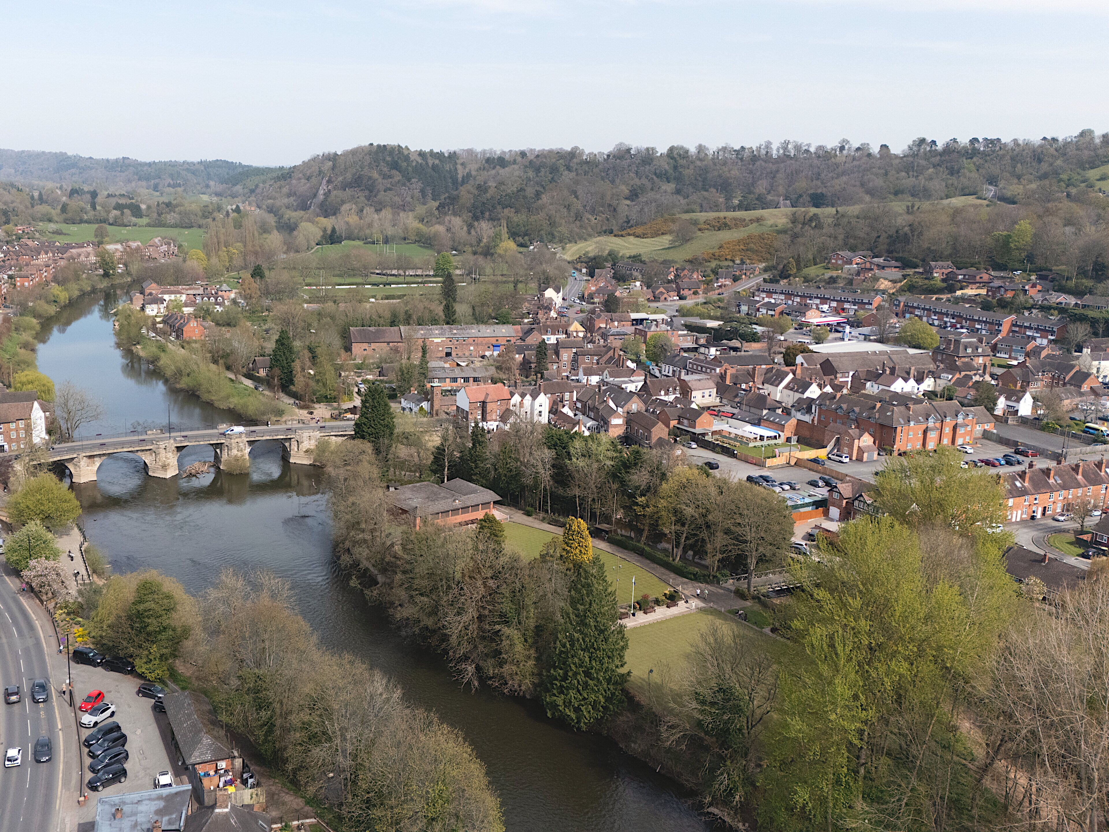 Ein Fluss, der durch eine Stadt fließt, mit einer Brücke, Häusern und viel Grün.
