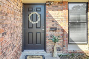 A dark brown front door with a wreath, a potted plant, and a welcome mat. - Tiger Town Retreat: Spacious 3-home Retreat! (Baton Rouge)