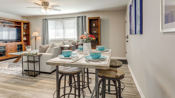 A dining area with a table set for four, a sofa, and a TV in the background. - Tiger Town Retreat: Spacious 3-home Retreat! (Baton Rouge)