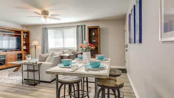 A dining area with a table set for four, a sofa, and a TV in the background.