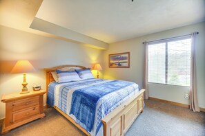 A bedroom with a bed, bedside lamps, a nightstand, a window with blinds, and a wall-mounted picture. - Seven Springs Escape! 2 Connected Ski-in/out Units (Champion)