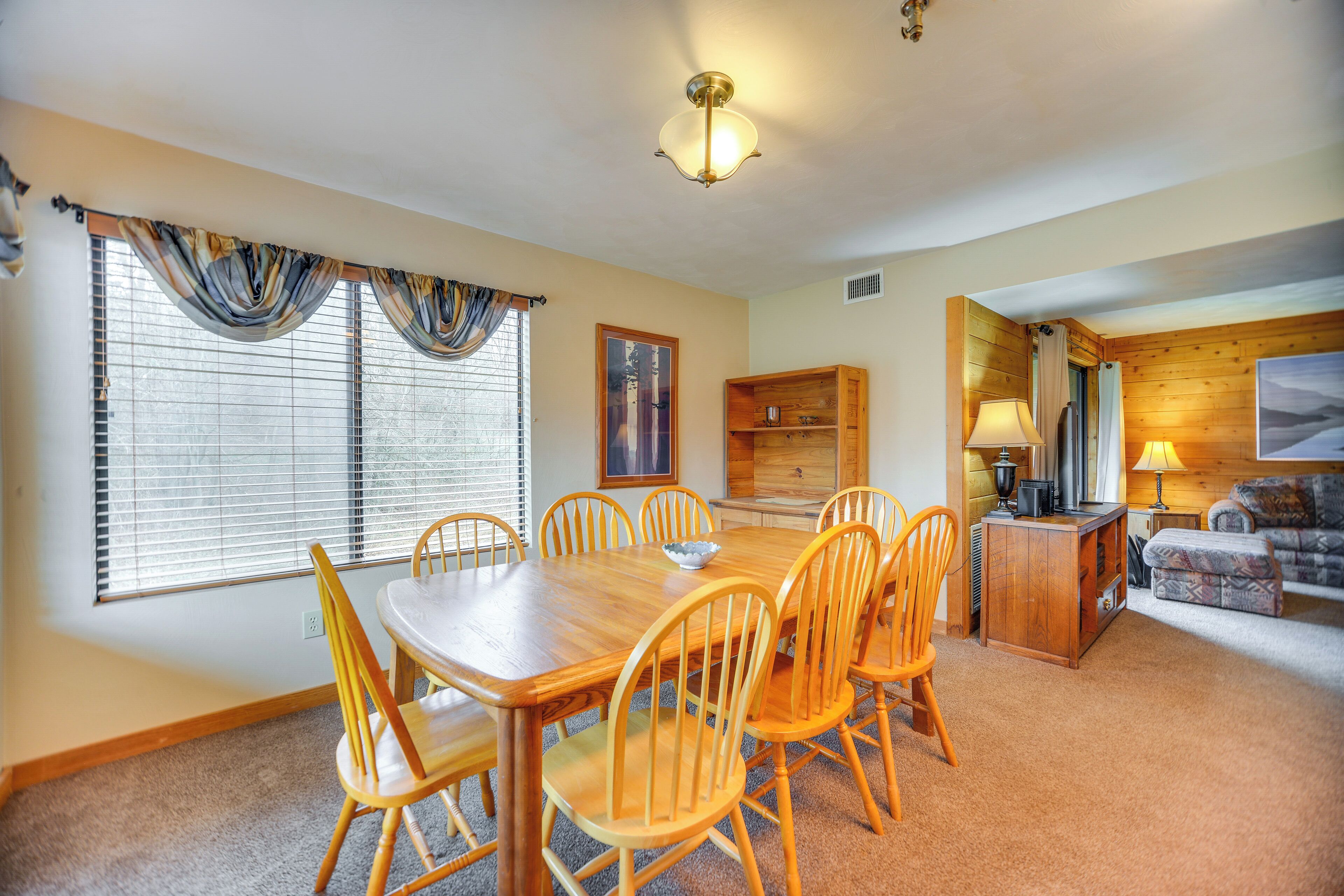 A dining area with a wooden table and chairs, a kitchen area with a refrigerator and stove, and a living room with a couch.