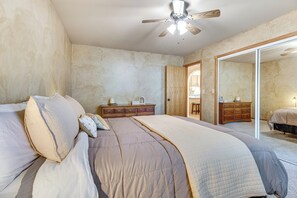 A bedroom with a large bed, a dresser, a mirror, and a ceiling fan. - Fishermen's Oasis! Steps to Dtwn & White River (Cotter)
