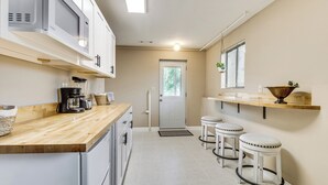 A kitchen with a microwave, coffee maker, and stools.