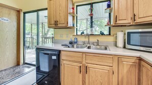 A kitchen with wooden cabinets, a dishwasher, a microwave, and a window with a view of the outdoors.