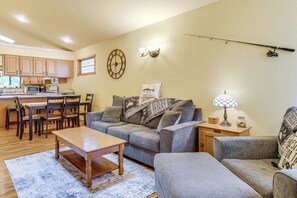 Un salon comprenant un canapé, un fauteuil, une table basse en bois et un coin repas avec des chaises et une table.