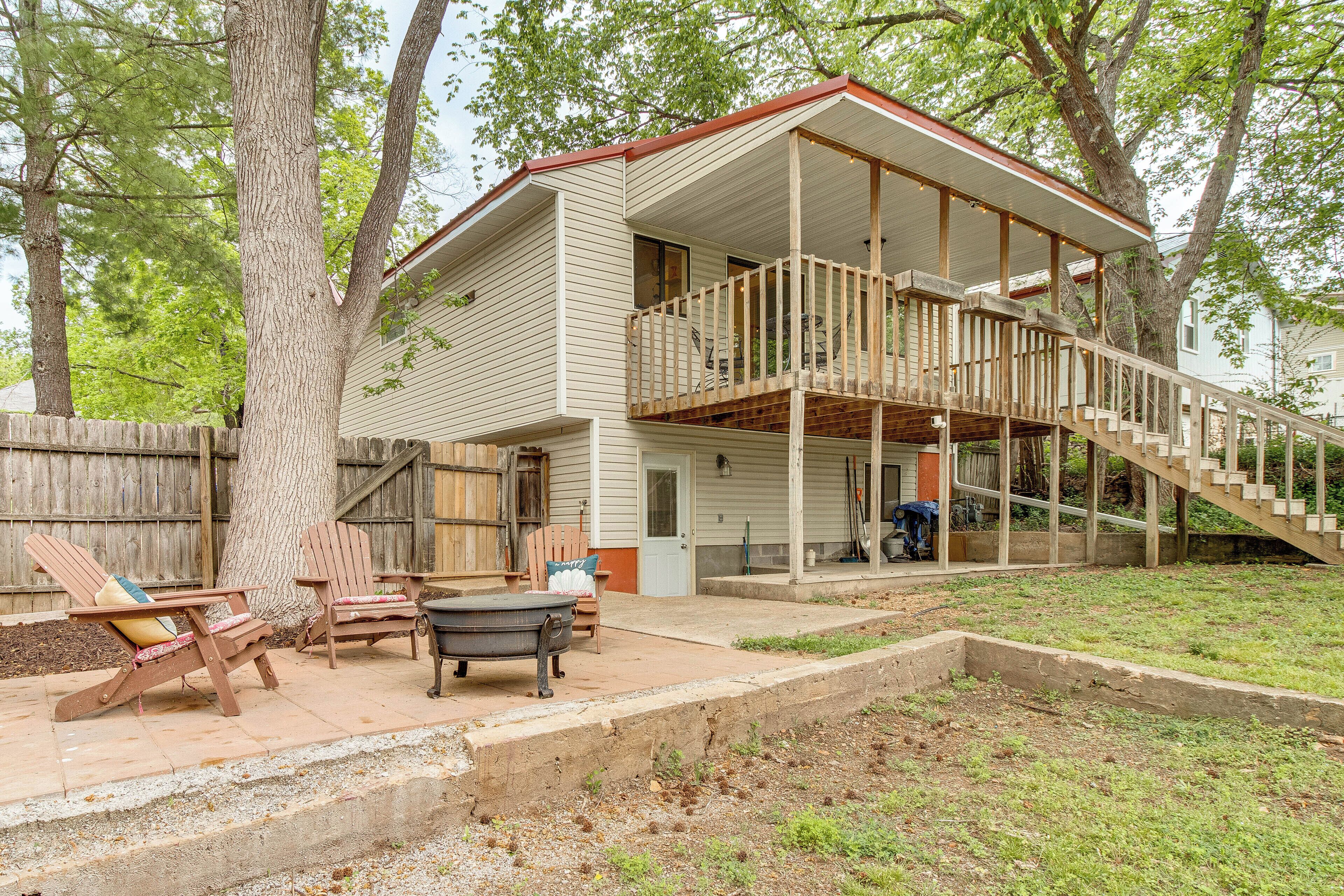 A two-story house with a wooden deck, a staircase, and outdoor furniture.