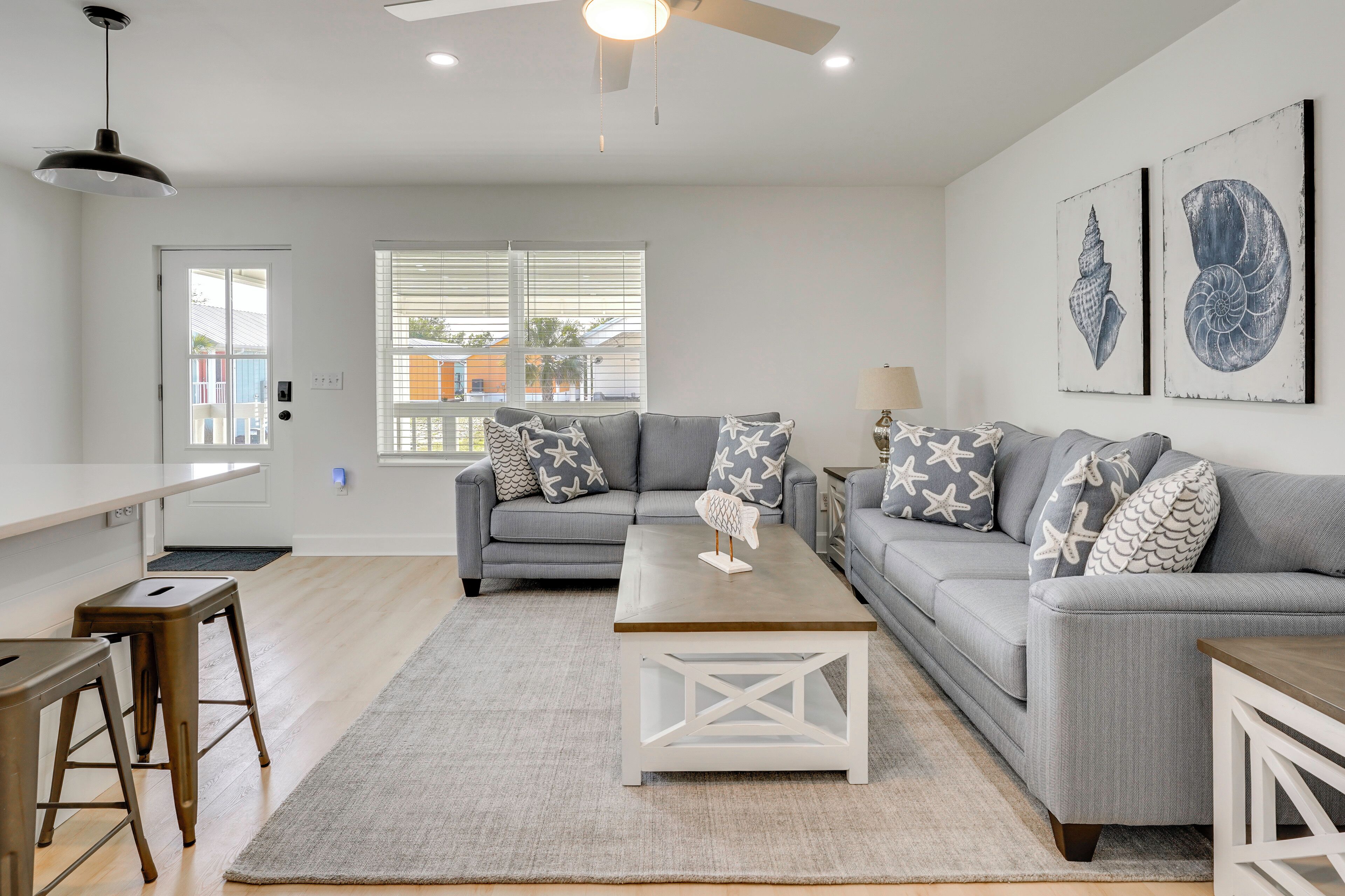 A modern living room with a grey sofa, white coffee table, and a ceiling fan.