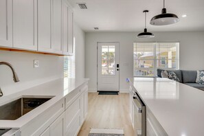 A modern kitchen with white cabinets, a large island, and pendant lighting. - Brand New Home in Steinhatchee With Rooftop Deck! (Steinhatchee)