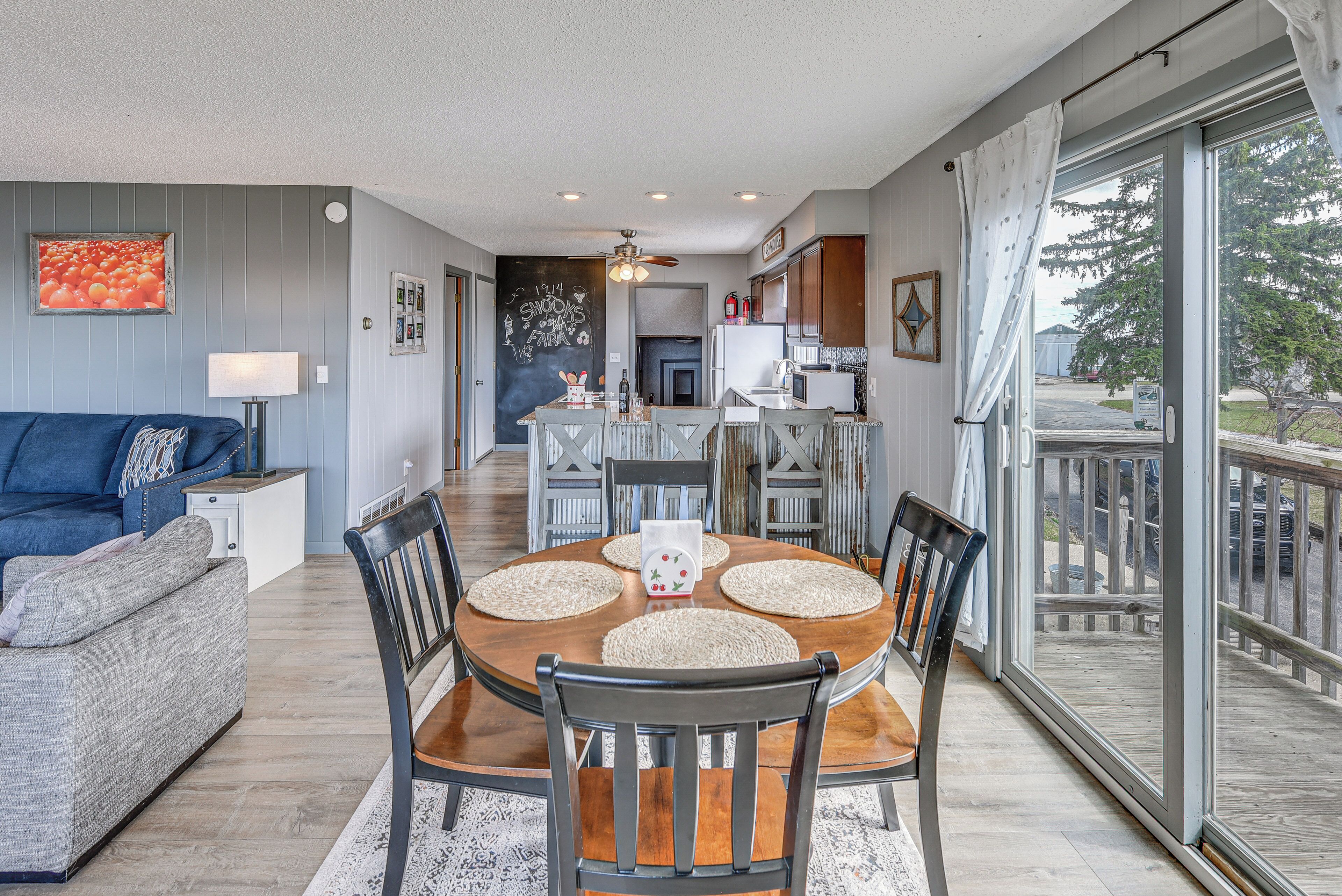 A dining area with a round table, chairs, and a view through a large glass door.