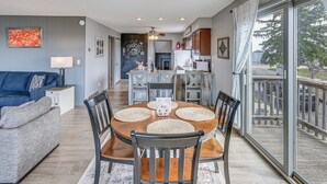 Un espace repas avec une table ronde, des chaises et une vue dégagée grâce à une grande porte vitrée.