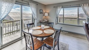 Un espace repas avec une table ronde, des chaises et une vue dégagée grâce à de grandes fenêtres.