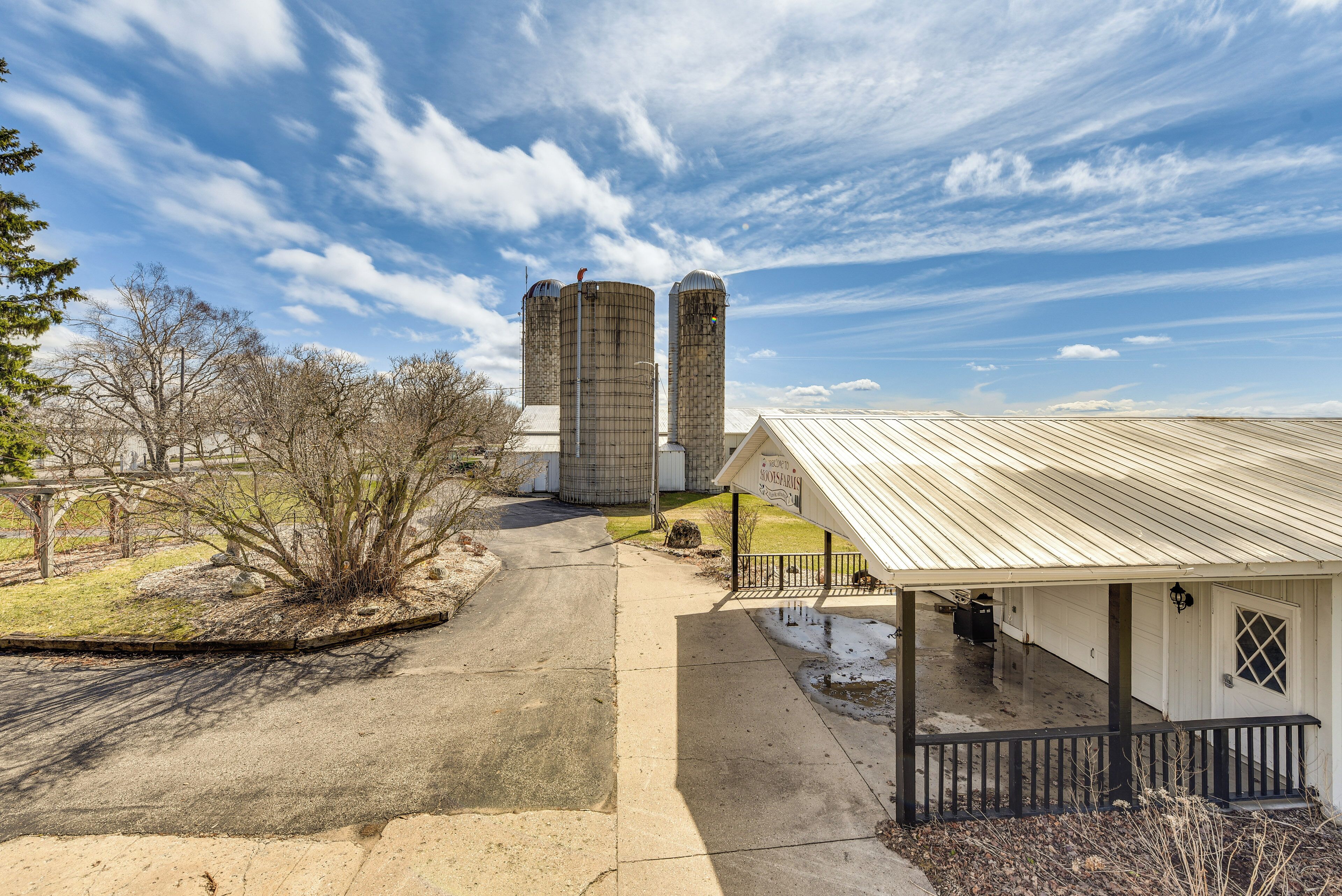 A rural property with two grain silos, a covered porch, and a detached garage.