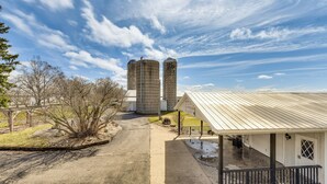 Une propriété rurale comprenant deux silos à céréales, une véranda et un garage séparé.