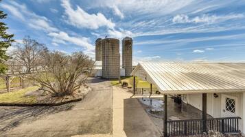 A rural property with two grain silos, a covered porch, and a detached garage.