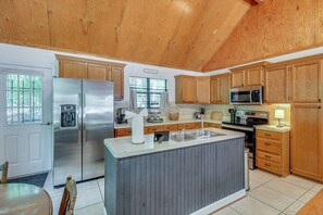 A kitchen with wooden cabinets, stainless steel appliances, a large island, and a window with curtains. - Game Room! Family Escape on Tims Ford Lake (Winchester)