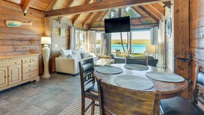 Un interior de madera con una mesa de comedor, sillas, un sofá y un televisor.