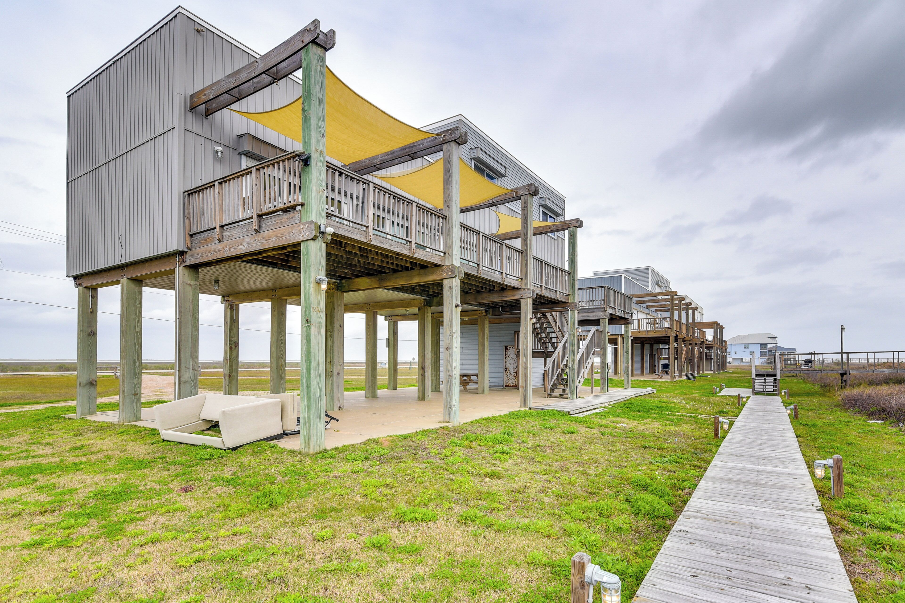 A coastal building with multiple levels, a wooden deck, and a grassy area.