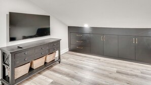 Una camera moderna con TV a schermo piatto, mobili scuri in legno e pavimento in legno chiaro.