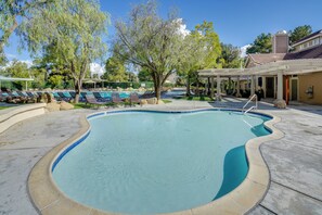 Ein Swimmingpool mit Liegestühlen, einer Pergola und einem Gebäude mit Ziegeldach.