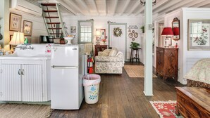A kitchen with a refrigerator, stove, and sink; a wooden ladder; a floral-patterned sofa; a wooden cabinet; and a red lamp. - Walk to Wineries: Charming Retreat in Augusta! (Augusta)