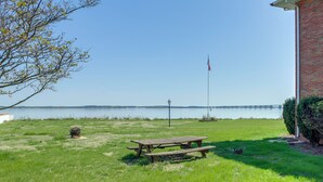 A grassy area with a picnic table, a flagpole, and a lamp post.
