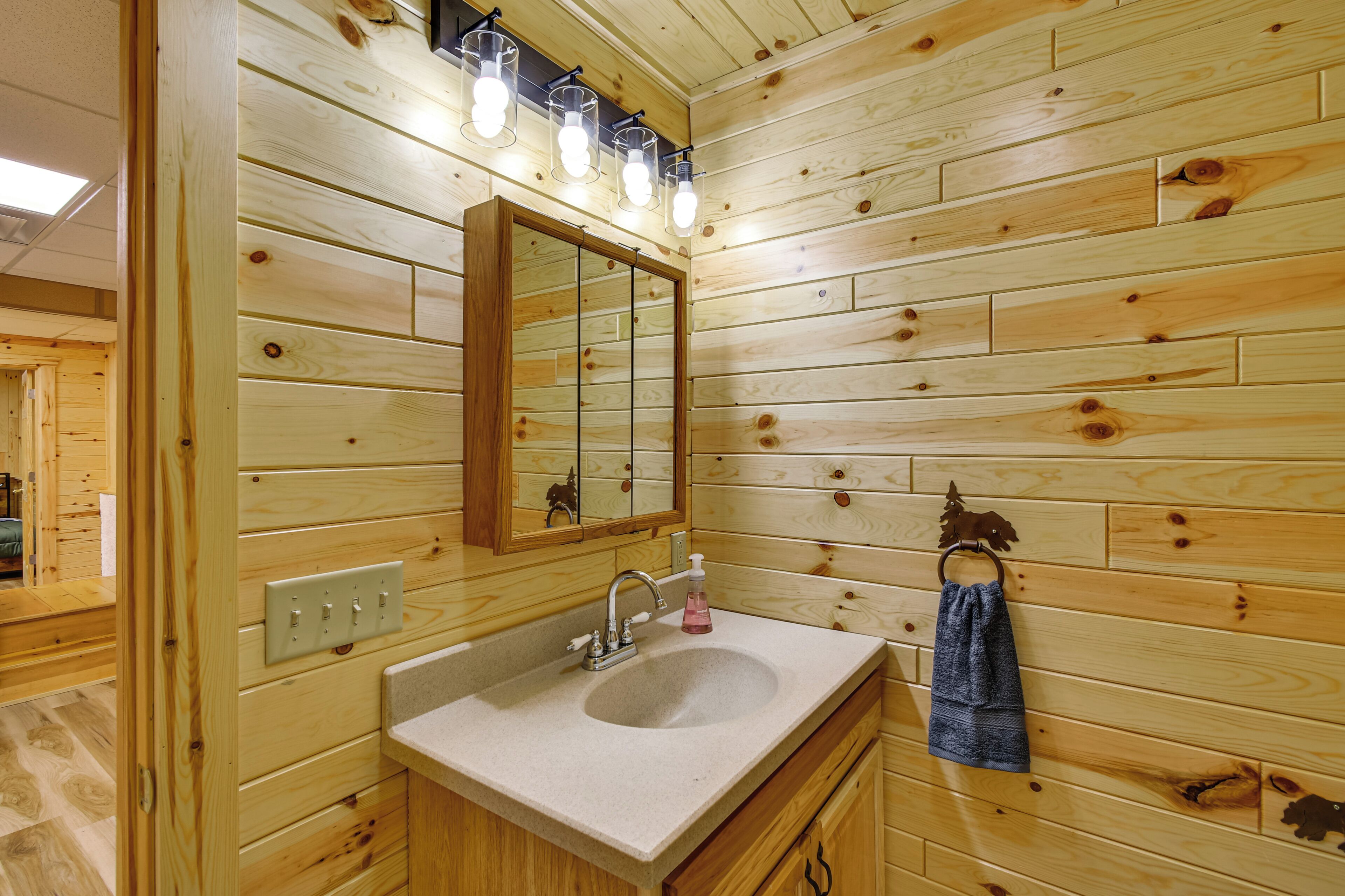 A wooden-paneled bathroom with a sink, mirror, and towel rack.