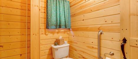 Un baño con paneles de madera, un inodoro, un pasamanos y una cortina.