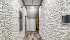 A hallway with geometric patterned walls, a wooden floor, and a cylindrical column.
