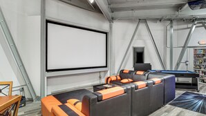 A modern indoor space with a large projection screen, a pool table, and a bookshelf.