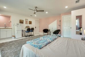 A bedroom with a bed, a desk, a chair, a ceiling fan, and a microwave. - Explore Atl! Cozy Couple's Hideaway in Ellenwood (Ellenwood)